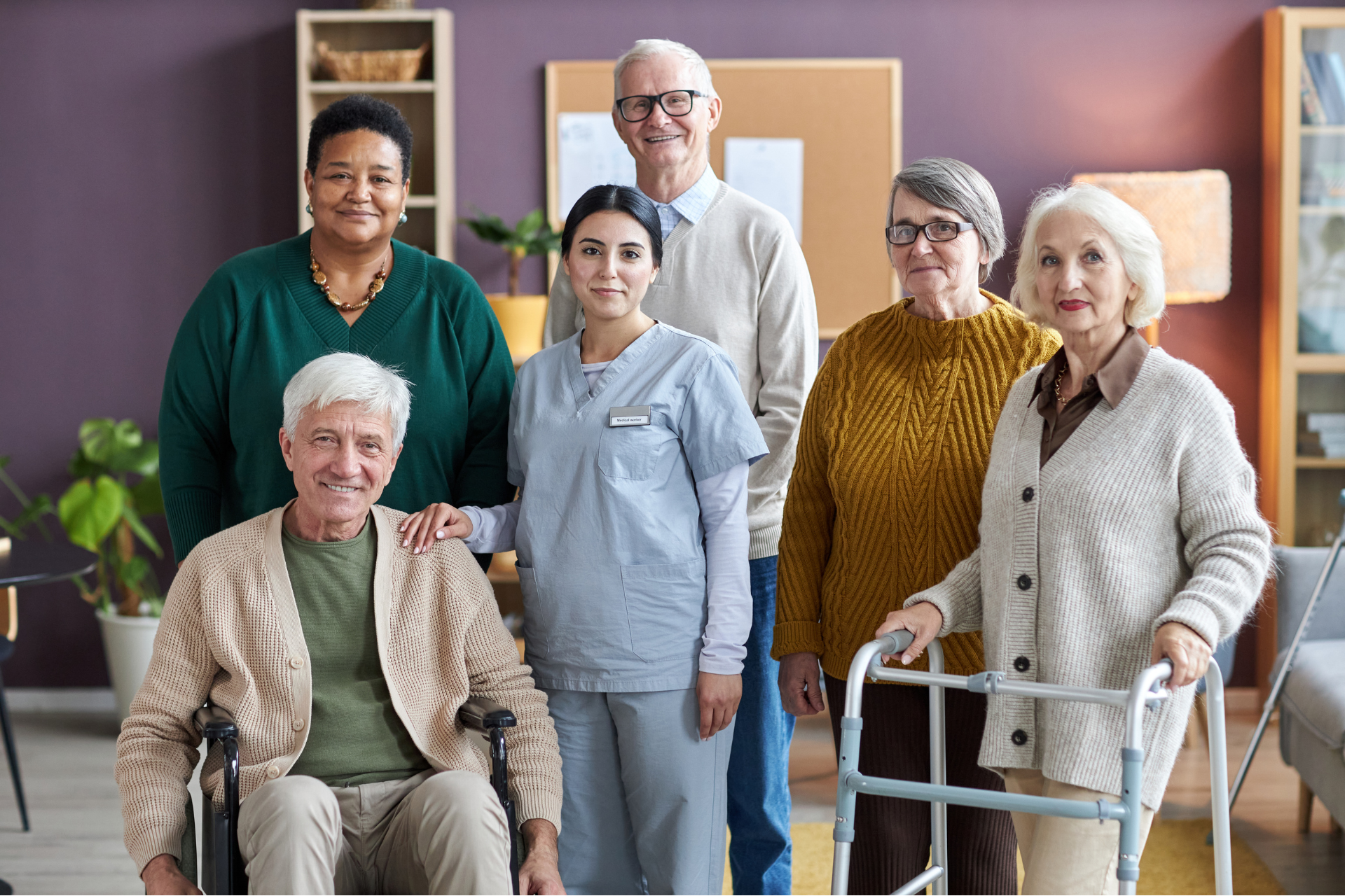 Seniors and a caregiver standing together, looking into the camera